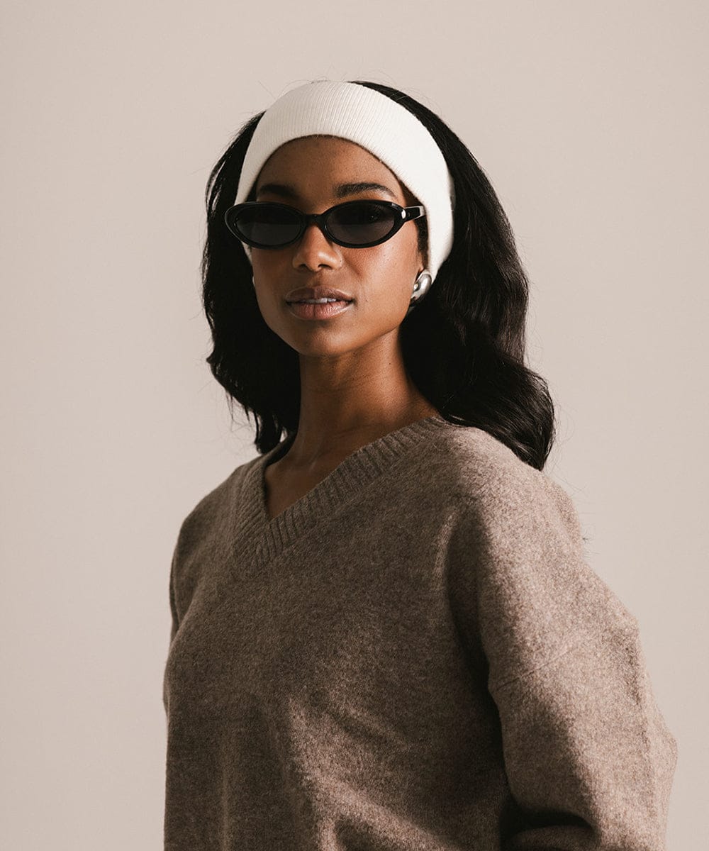 Woman wearing a white headband and sunglasses with a neutral background #color_ivory