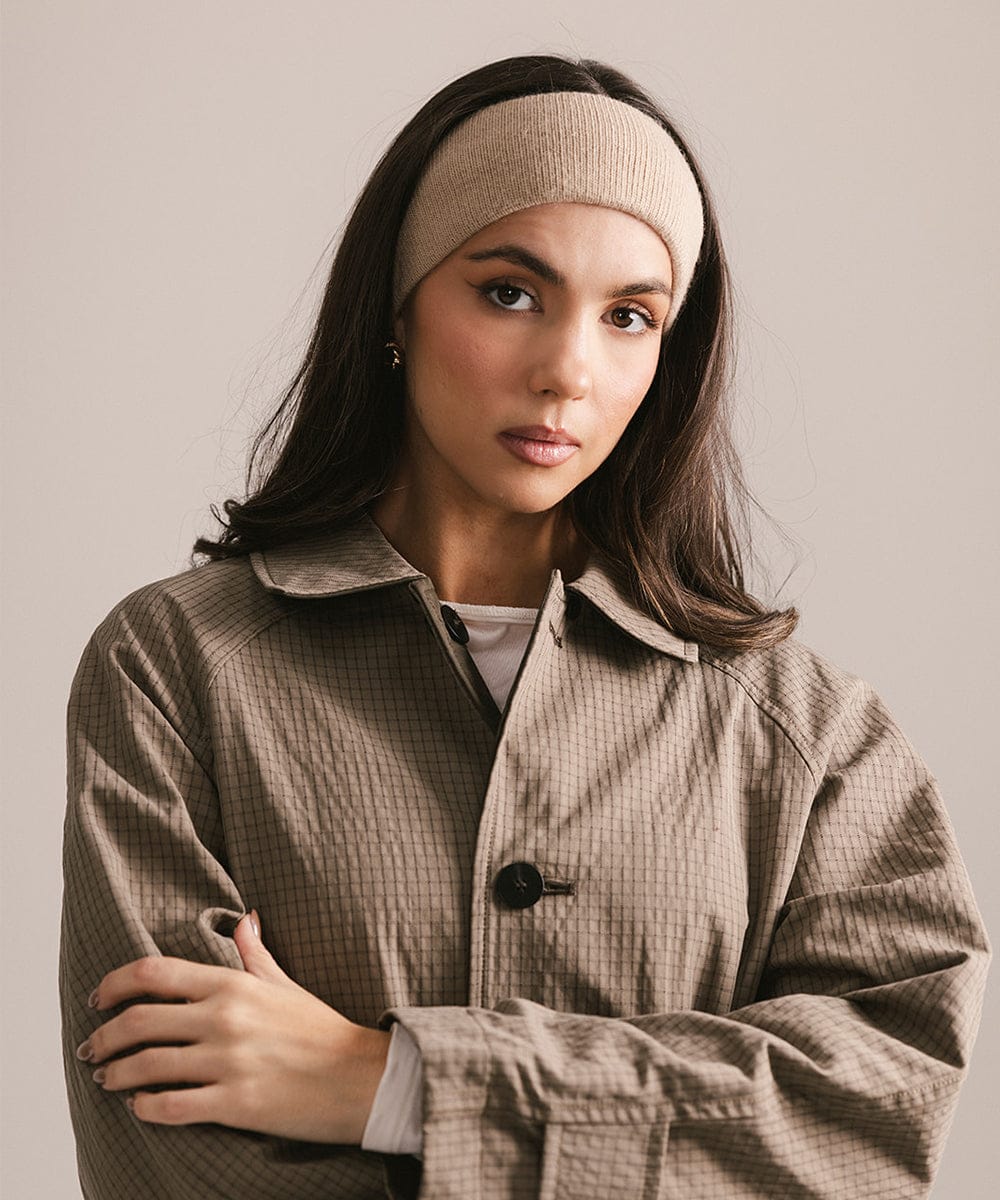 Woman wearing a beige headband and coat against a plain background #color_tan