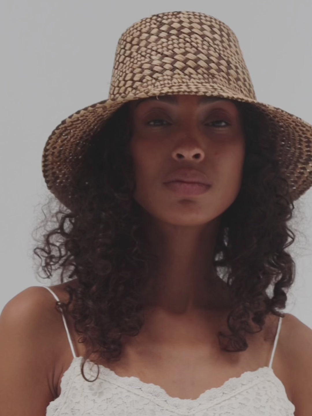 Woman wearing a woven bucket hat against a plain background #color_natural brown