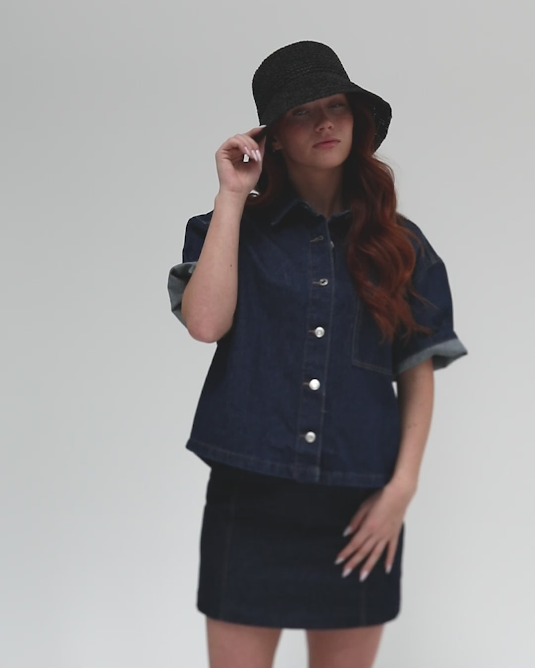 Woman wearing a black crochet packable bucket hat, a denim shirt and denim skirt, posing against a plain background #color_black