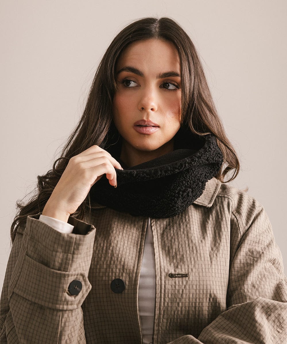 Woman wearing a black scarf and brown coat against a neutral background #color_black