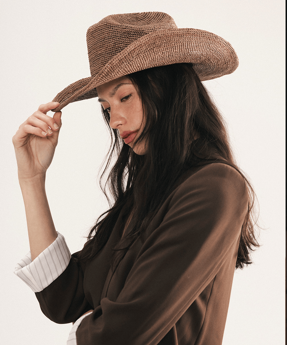 Woman wearing a chocolate colored straw cowboy hat on a white background #color_chocolate