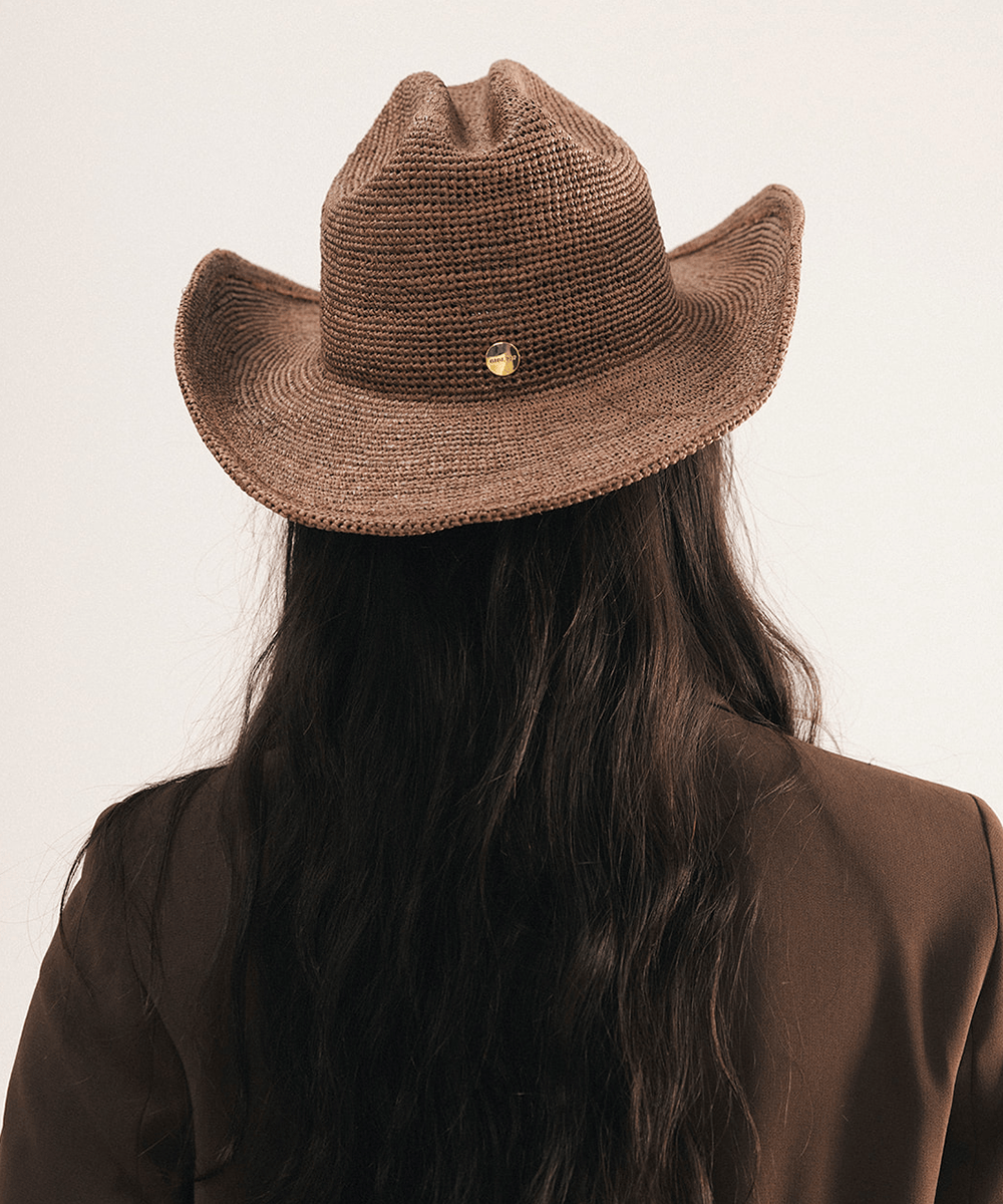Woman wearing a chocolate colored straw cowboy hat on a white background #color_chocolate