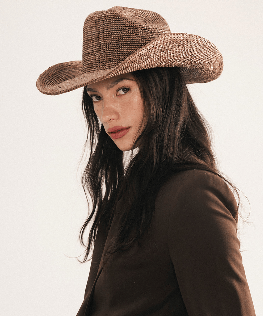 Woman wearing a chocolate colored straw cowboy hat on a white background #color_chocolate