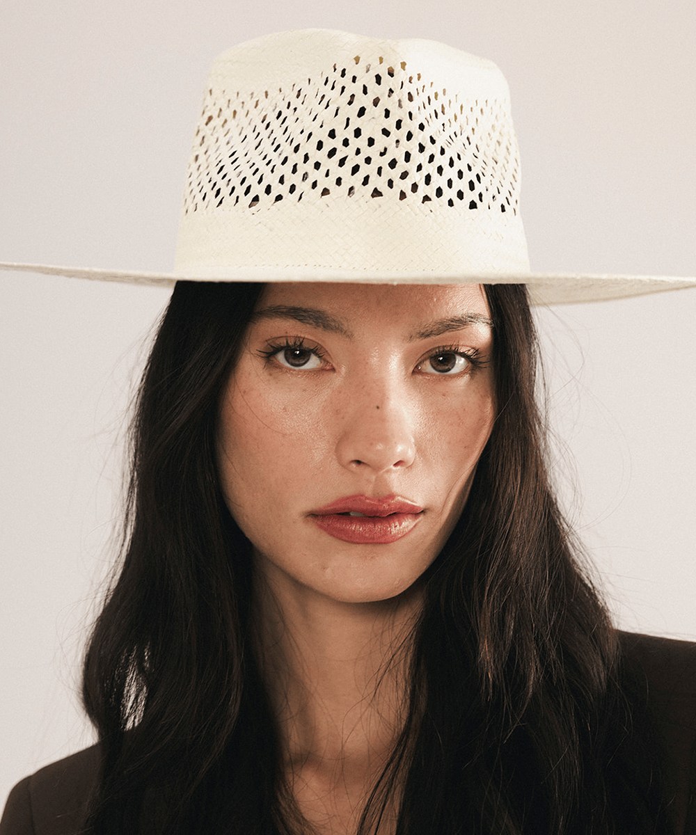 Woman wearing a natural white straw fedora hat with a wide brim and intricate venting details. #color_natural white