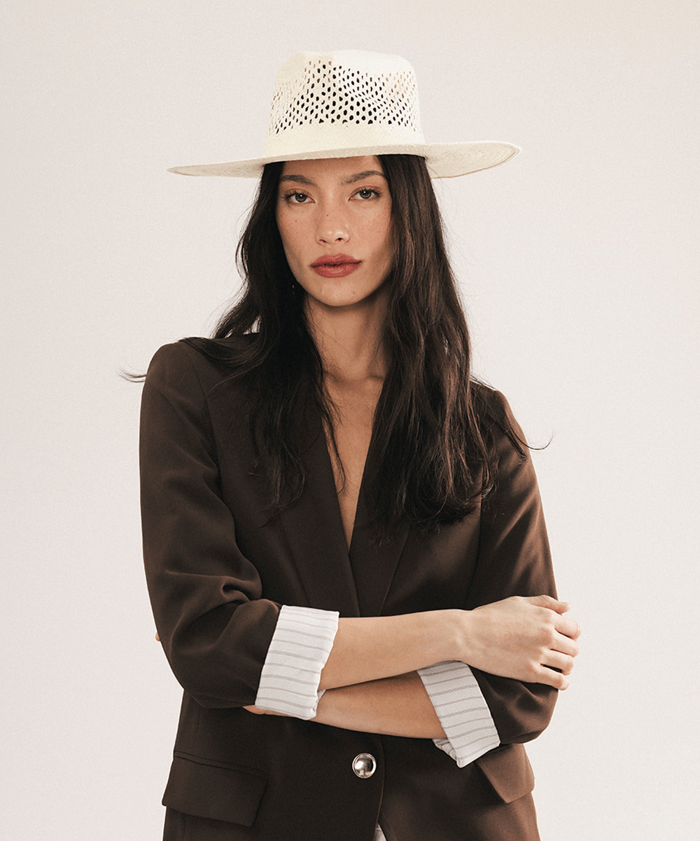 Woman wearing a natural white straw fedora hat with a wide brim and intricate venting details. #color_natural white