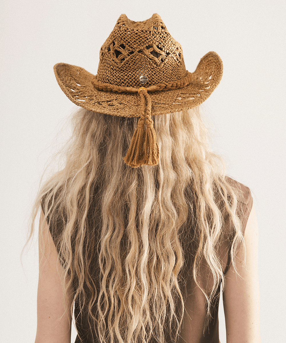 Woman wearing a honey colored paper rope straw cowboy hat with a classic cattleman crown and a wide brim featuring large venting details for airflow against a plain background #color_honey