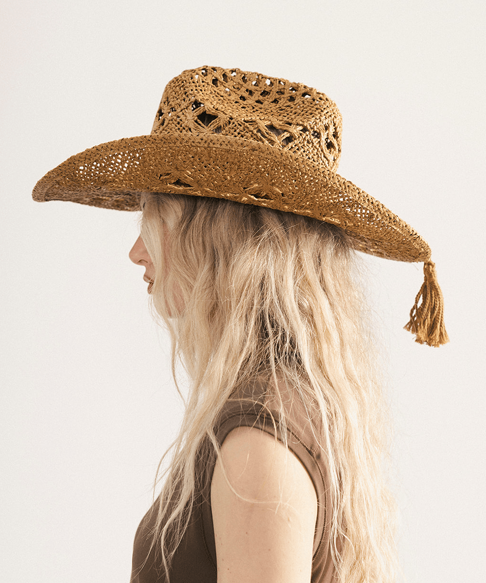 Woman wearing a honey colored paper rope straw cowboy hat with a classic cattleman crown and a wide brim featuring large venting details for airflow against a plain background #color_honey