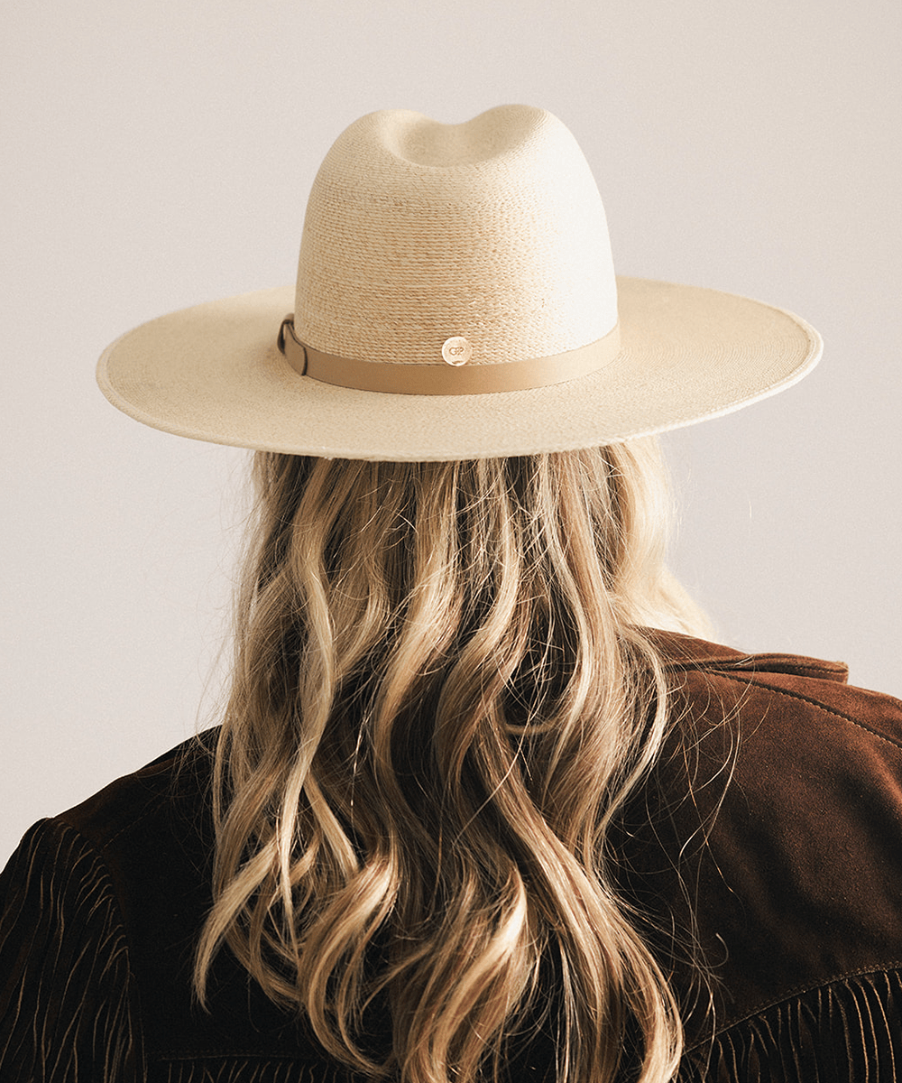 Woman wearing a natural colored Blake Wide Brim Fedora Hat with a flat wide brim and a tonal genuine leather band, displayed against a plain background. #color_natural