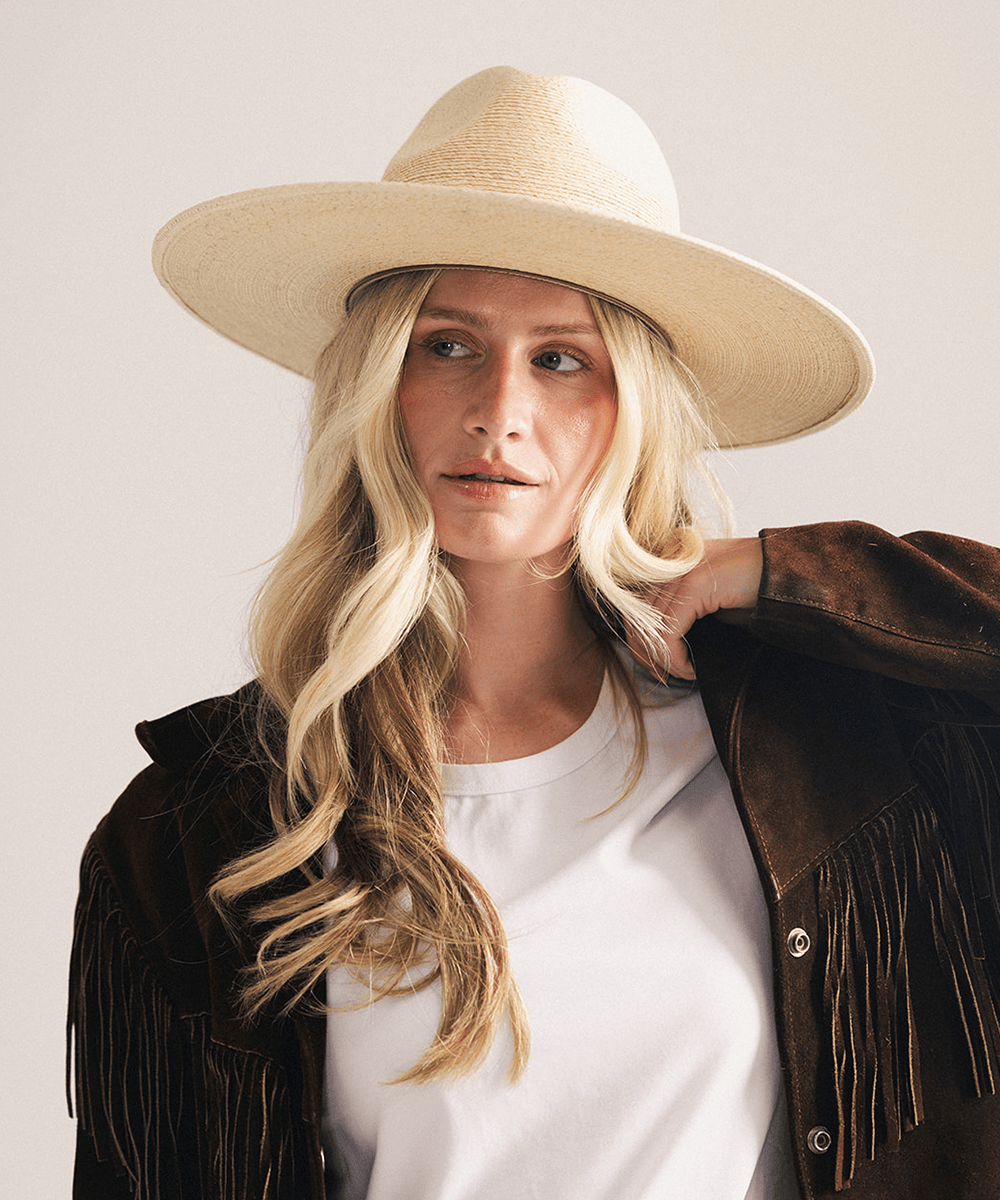 Woman wearing a natural colored Blake Wide Brim Fedora Hat with a flat wide brim and a tonal genuine leather band, displayed against a plain background. #color_natural