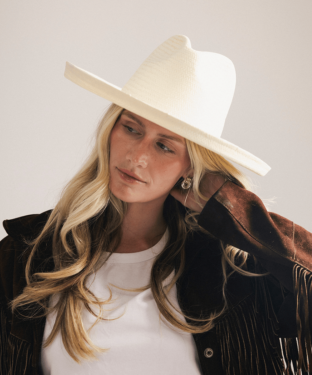 Woman wearing a white pencil brim fedora hat made of paper straw, displayed against a white background. #color_white