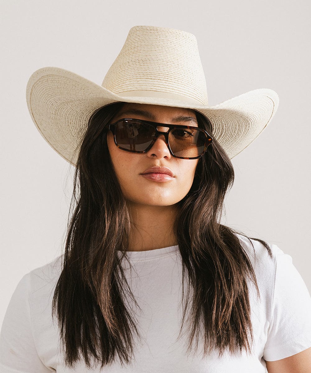 Woman wearing a straw cowboy hat and sunglasses on a plain background #color_tortoise