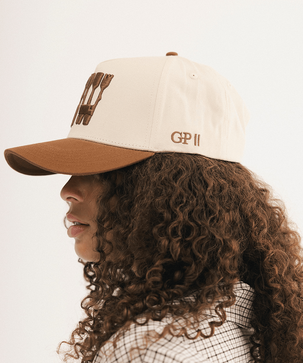 Woman's side view wearing a baseball cap on a white background #color_cream - tan