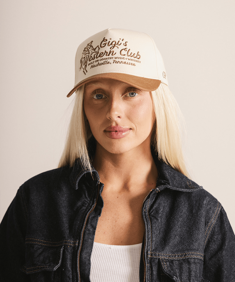 Woman wearing a beige cap with text and a denim jacket on a plain background #color_cream - caramel