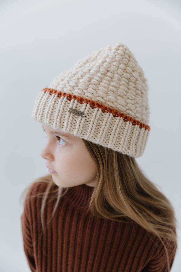 Gigi Pip beanies for kids - Kids Vail Beanie - 100% acrylic chunky knit beanie in a universal kids size featuring a comfortable plush inner band and the Gigi Pip logo on a metal bar in the front [cream-burnt orange]